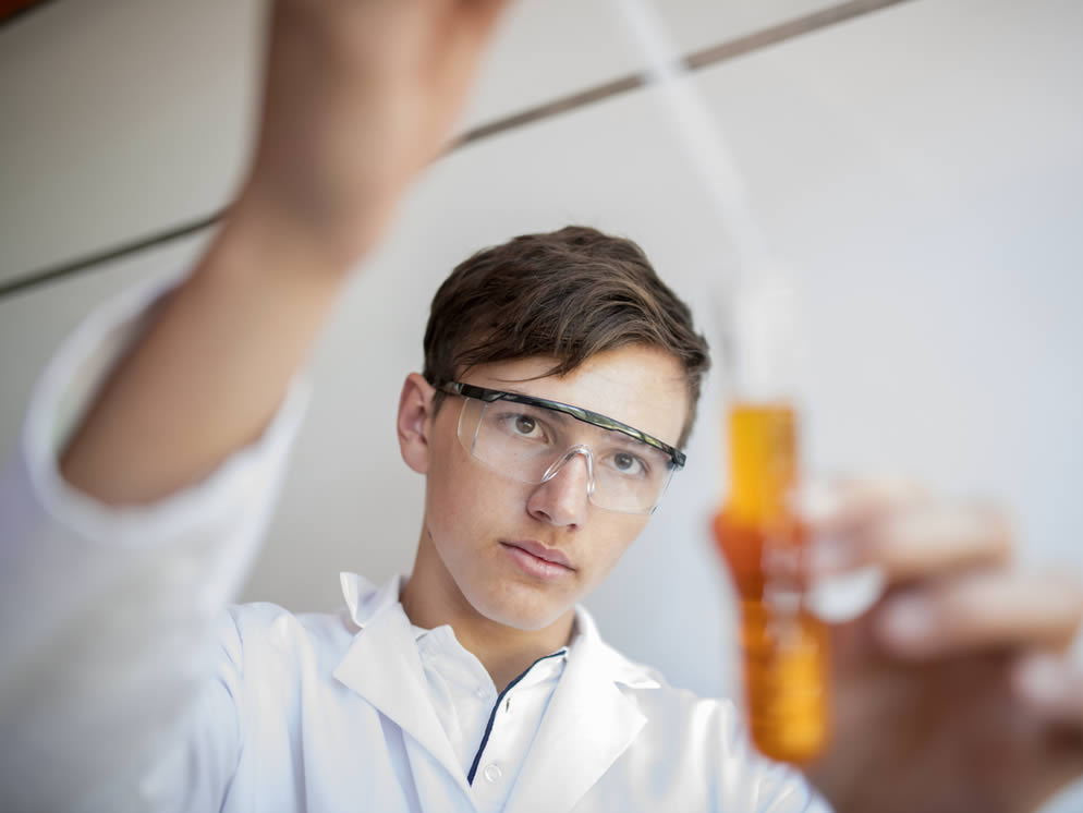 Junger Mann kontrolliert Saft in einem Reagenzglas