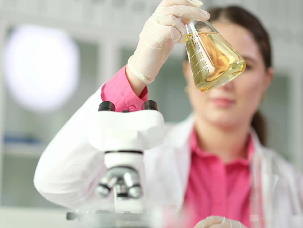 Junge Frau analysiert Saft in einem Laborglas