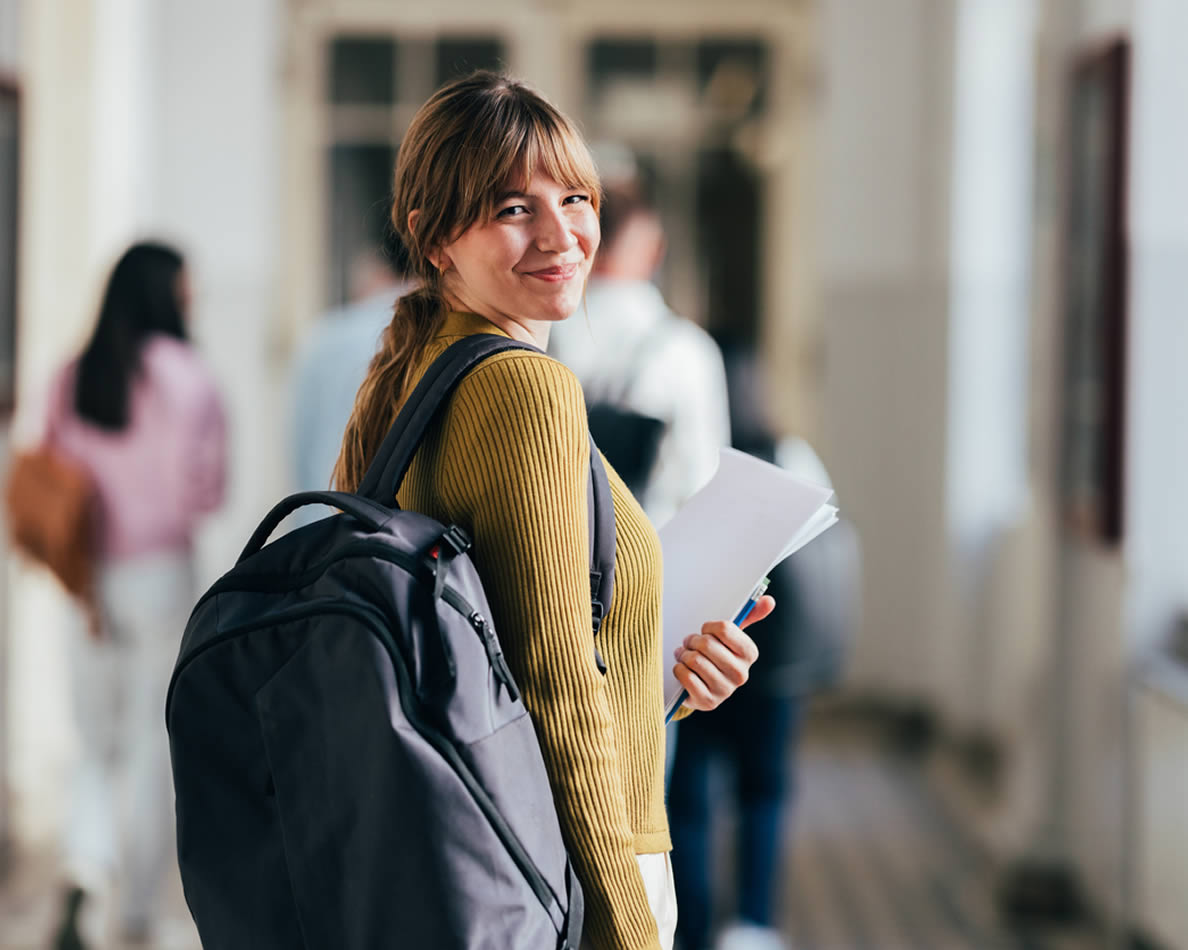 Junge Frau geht lächelt den Schulflur entlang