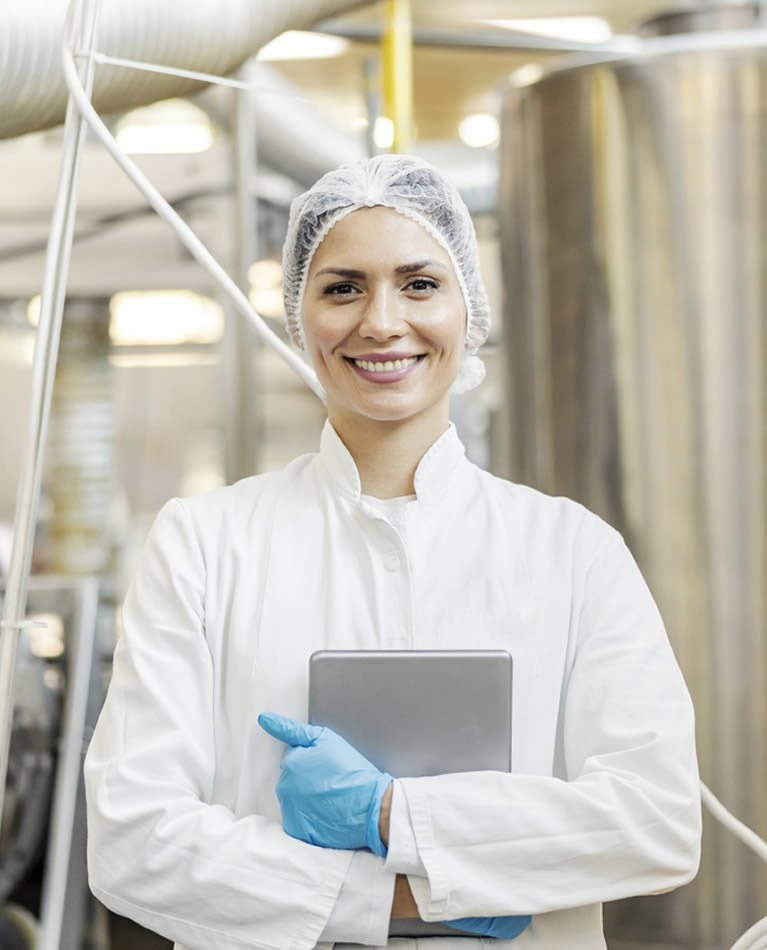 Lächelnde Frau steht vor einer Produktionsmaschine
