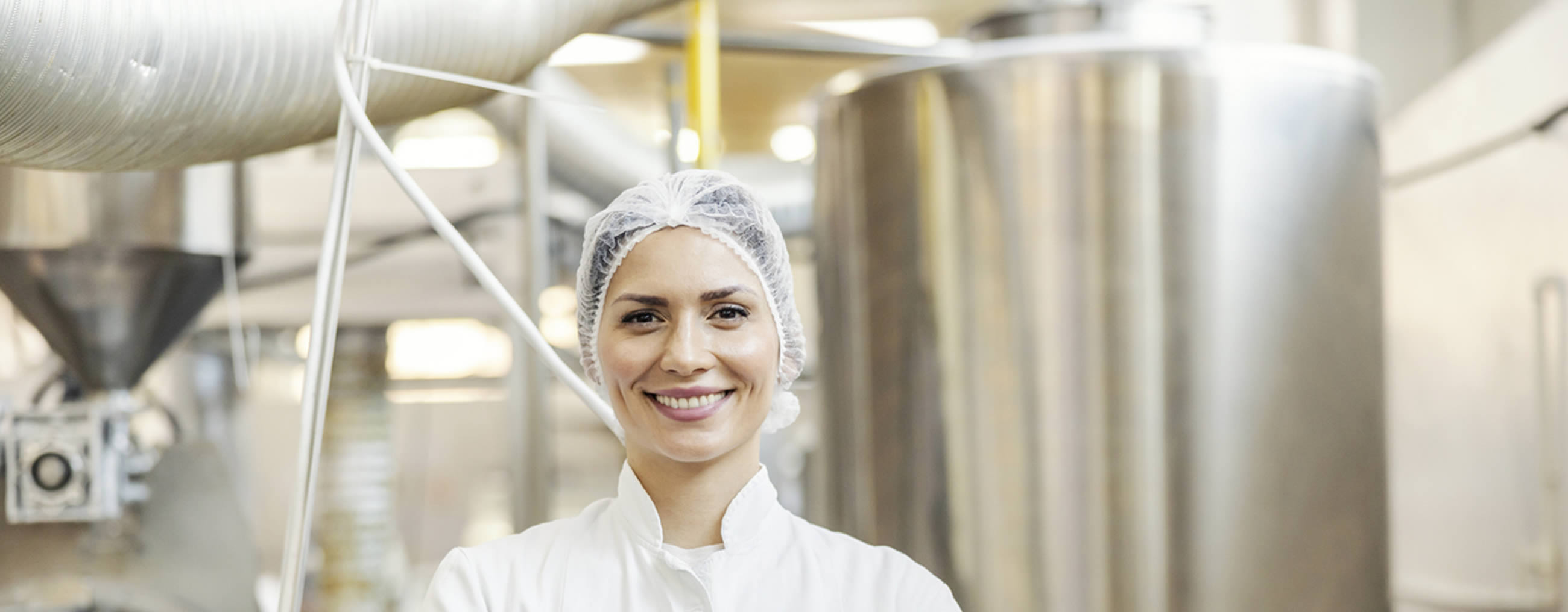 Lächelnde Frau steht vor einer Produktionsmaschine