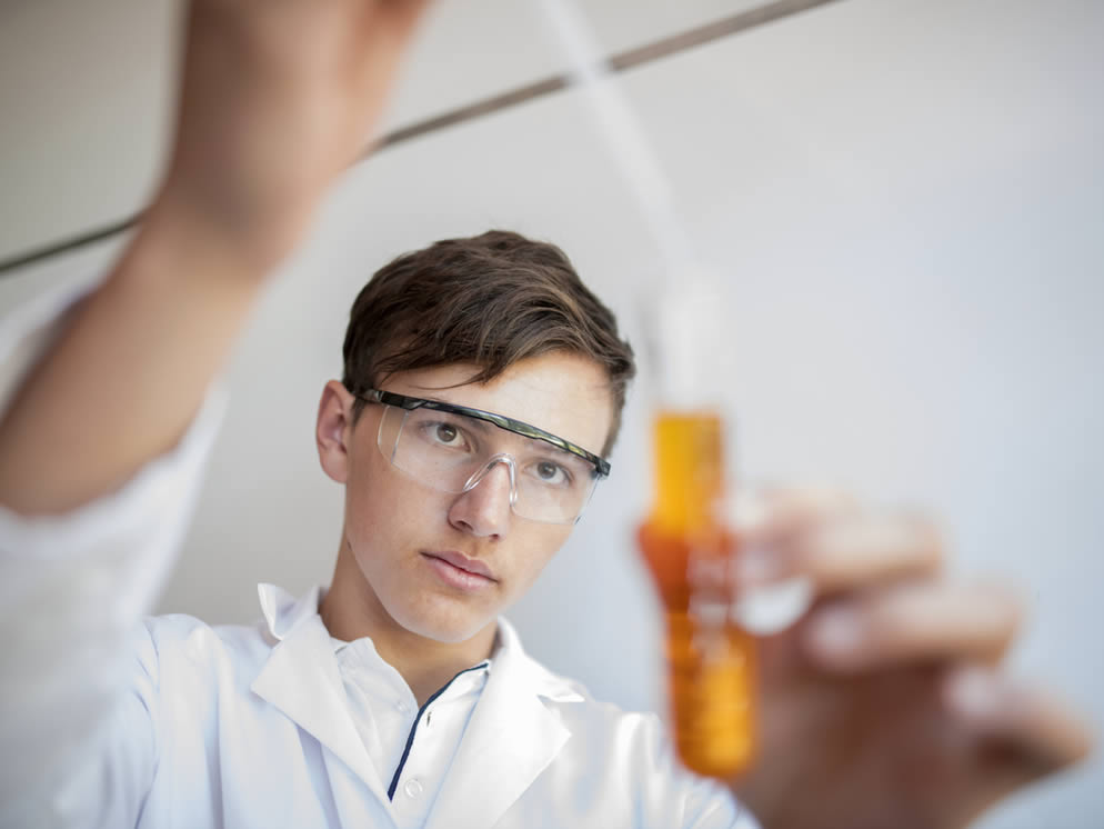 Junger Mann kontrolliert Saft in einem Reagenzglas