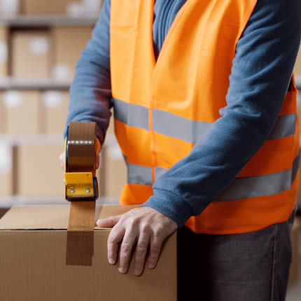 Lagerarbeiter versiegelt ein Paket mit Klebeband