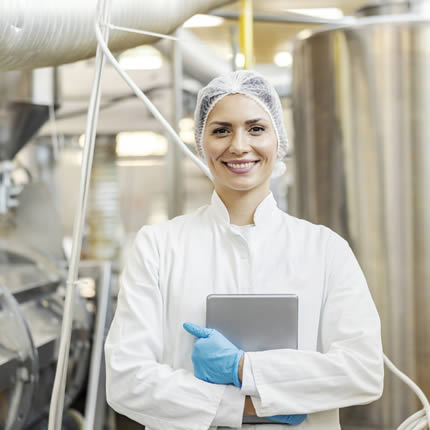 Lächelnde Frau steht vor einer Produktionsmaschine