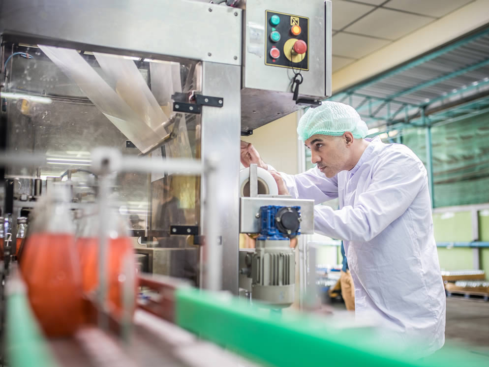 Junger Mann kontrolliert den Prozess an einer Maschine