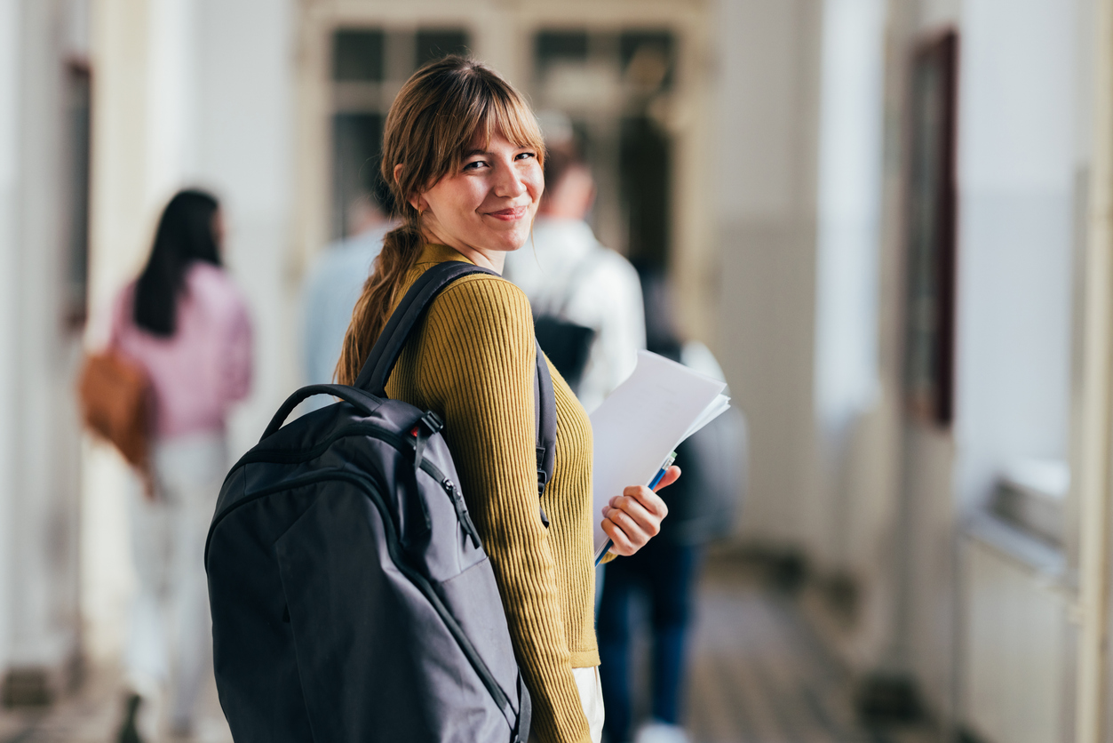 Junge Frau geht lächelt den Schulflur entlang