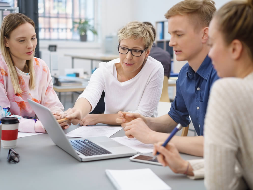 Vier Personen arbeiten an einem Laptop zusammen