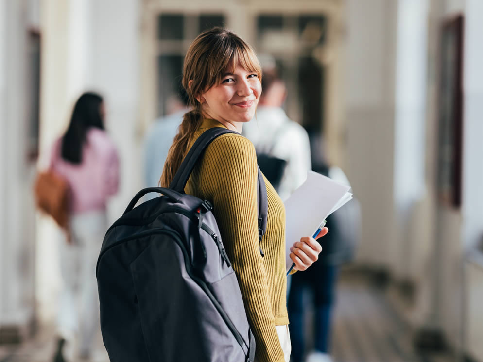 Junge Frau geht lächelt den Schulflur entlang