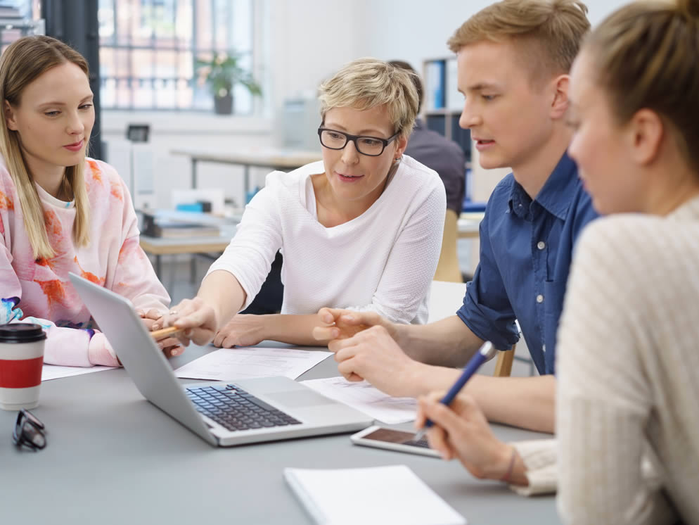 Vier Personen arbeiten an einem Laptop zusammen