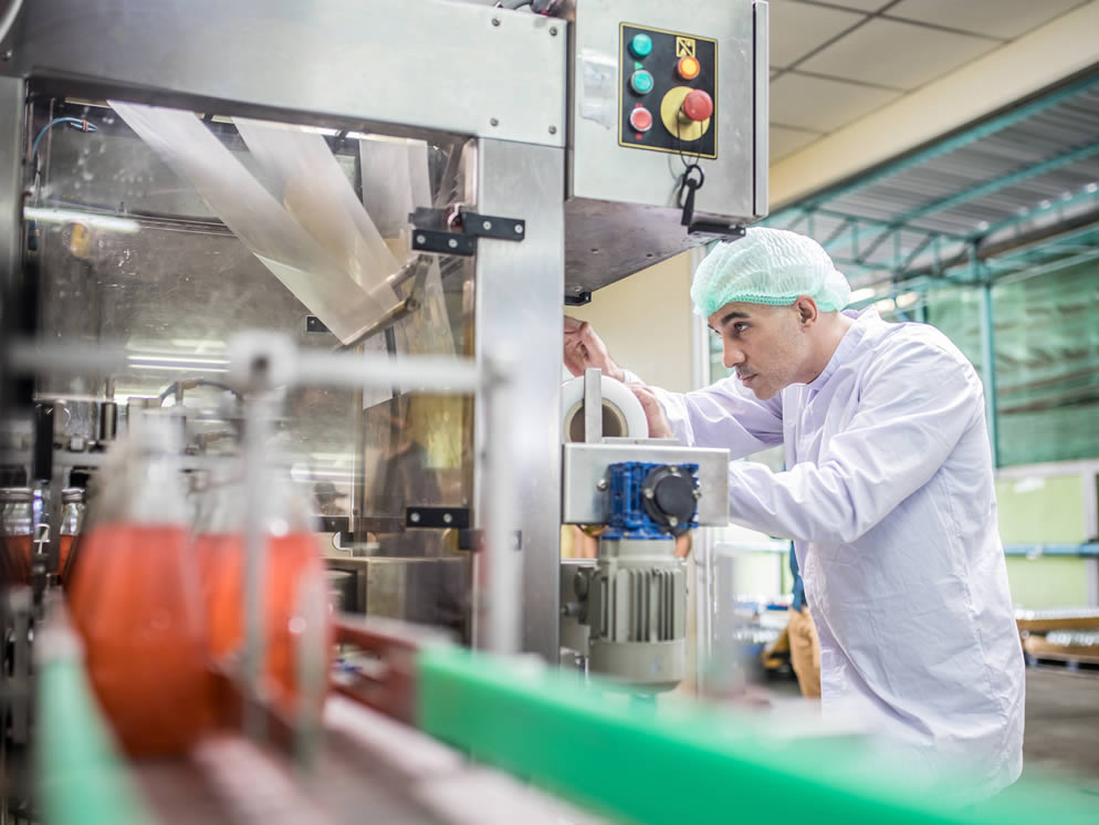 Junger Mann kontrolliert den Prozess an einer Maschine