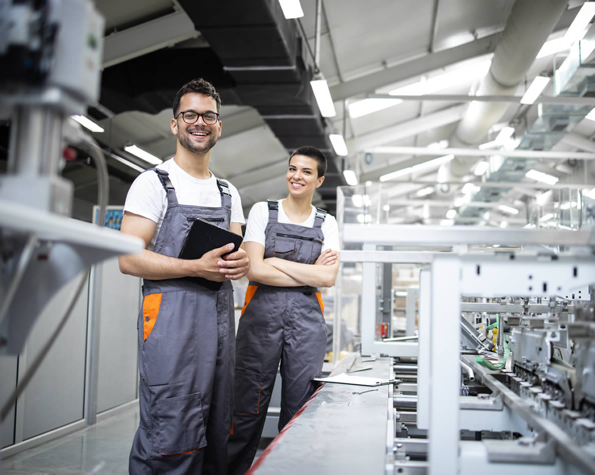 Ein Mann und eine Frau stehen in einer Produktionshalle