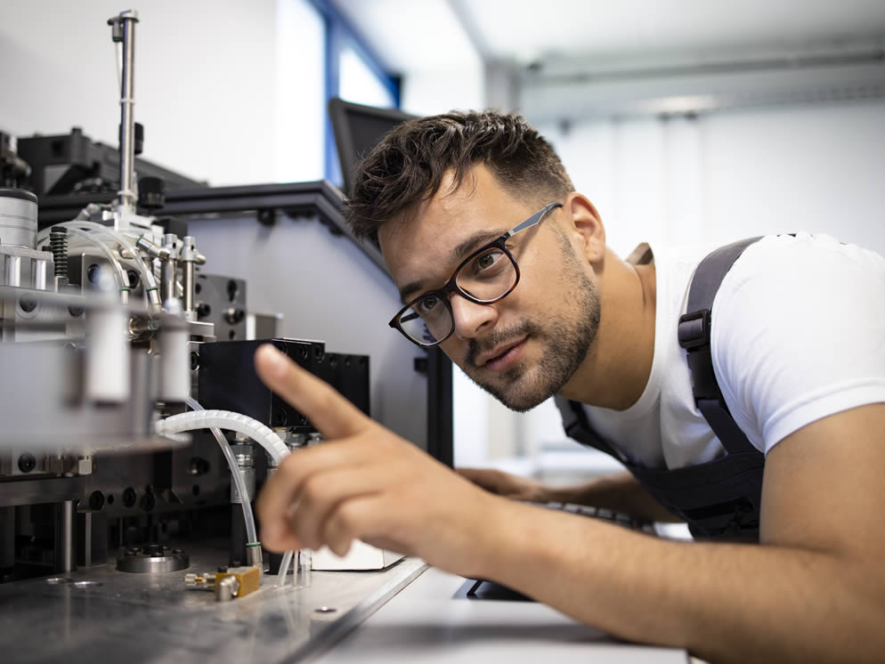 Mann überprüft Maschine in einer Produktionshalle